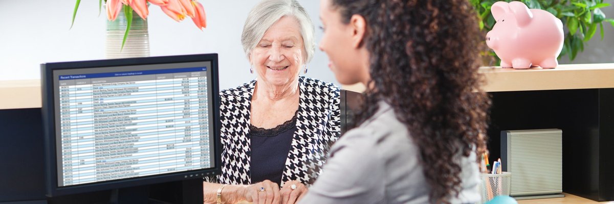 Older woman getting assistance from a bank teller.
