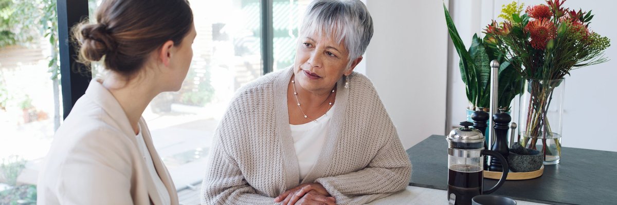 An older woman has a conversation over paperwork with a young professional.