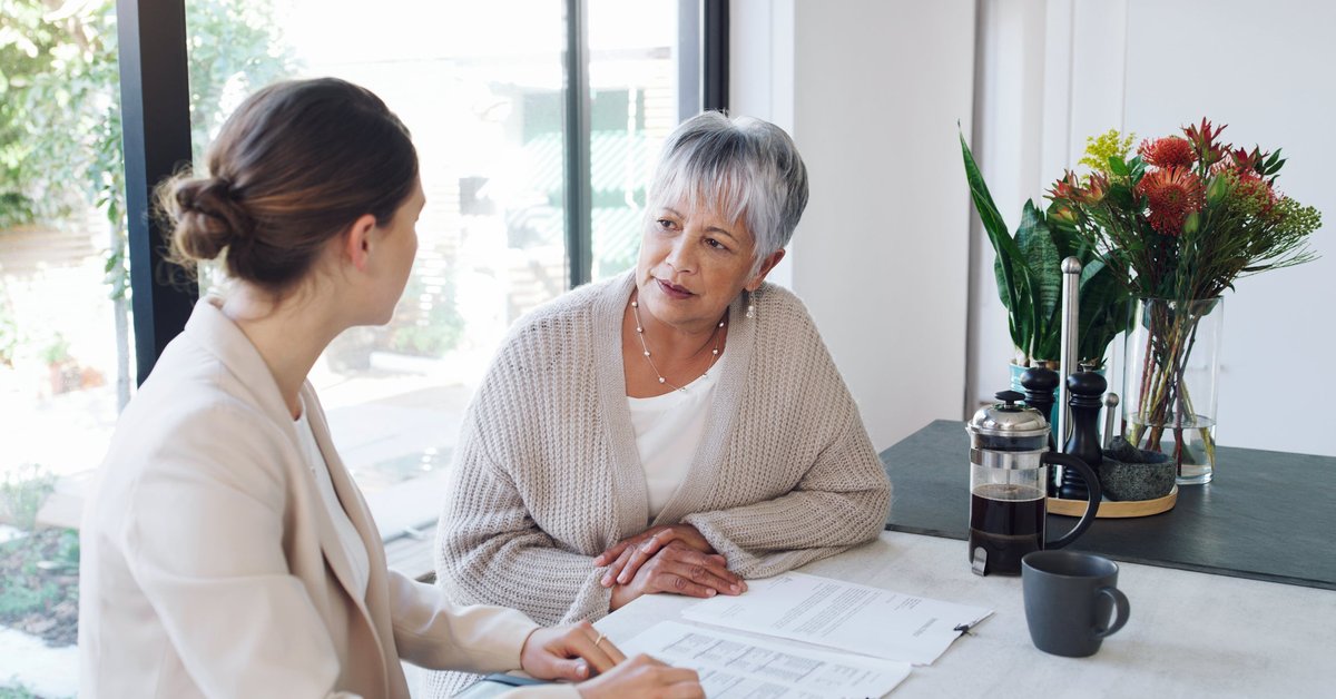 An older woman has a conversation over paperwork with a young professional.