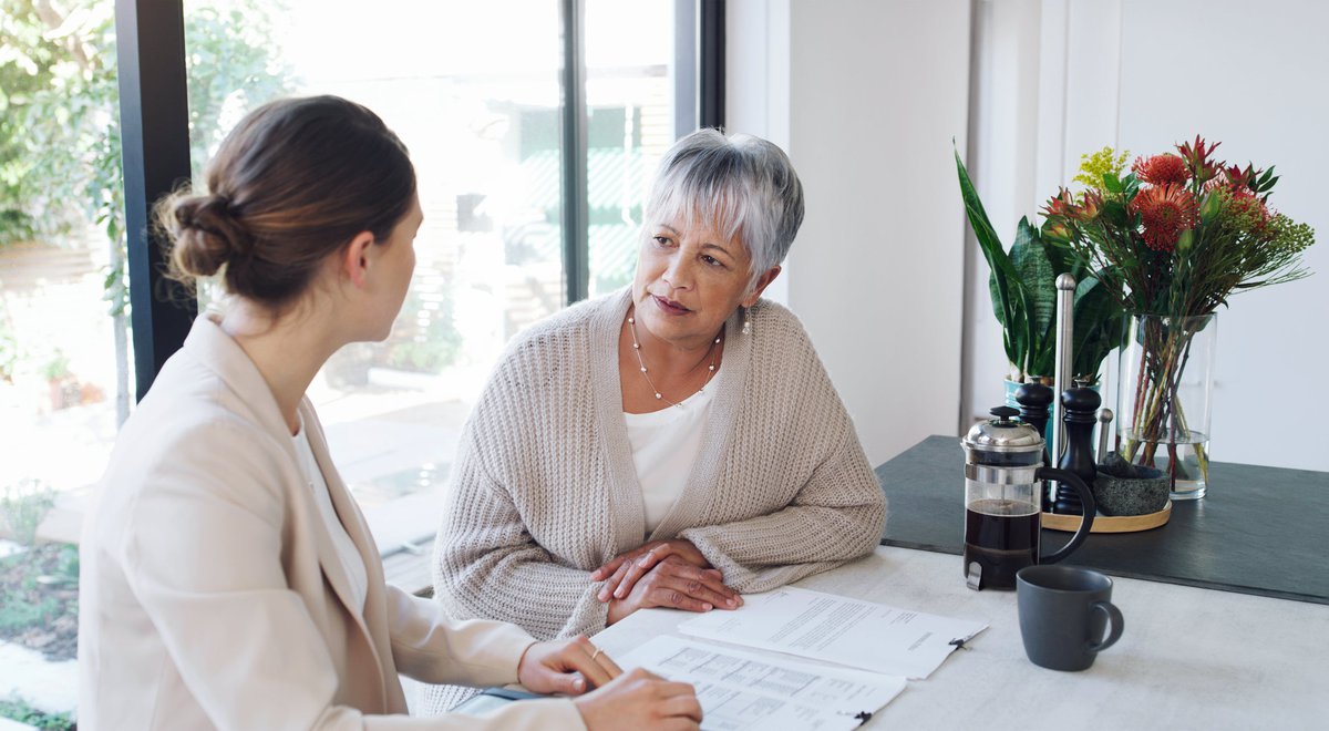 An older woman has a conversation over paperwork with a young professional.