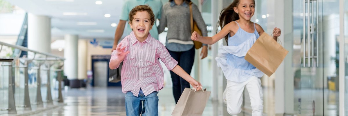 Parents and kids at shopping mall with shopping bags.