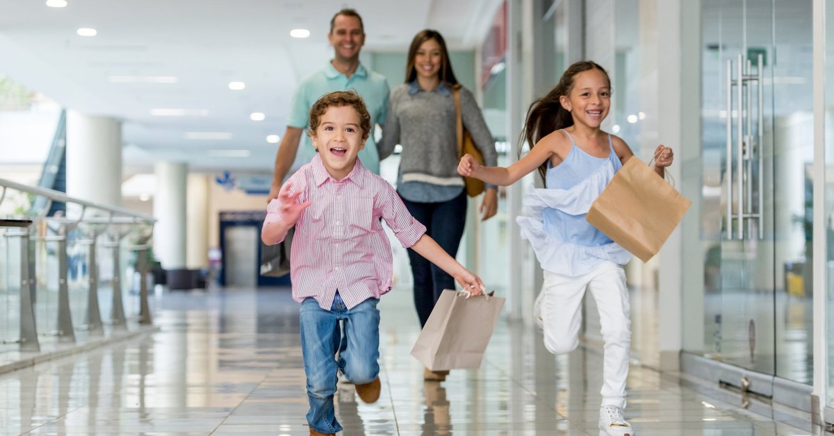 Parents and kids at shopping mall with shopping bags.