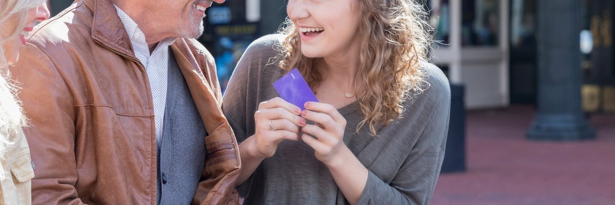 Parents giving credit card to excited teen daughter.