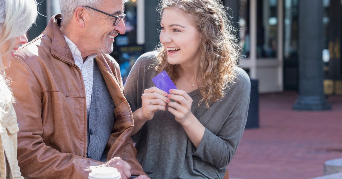 Parents giving credit card to excited teen daughter.