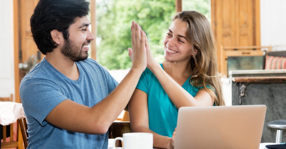 Young Couple High-Fiving In Front Of Laptop