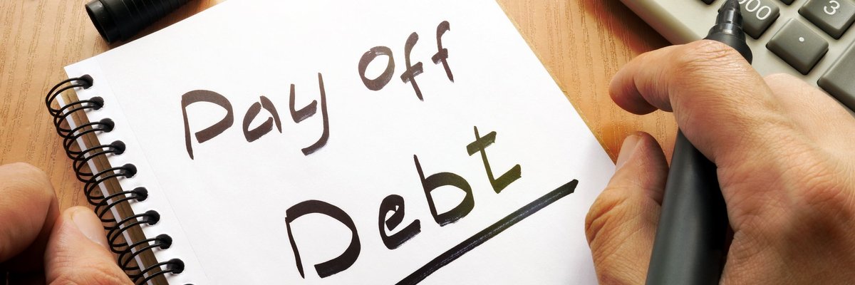 A notepad with "Pay off debt" written in black marker.