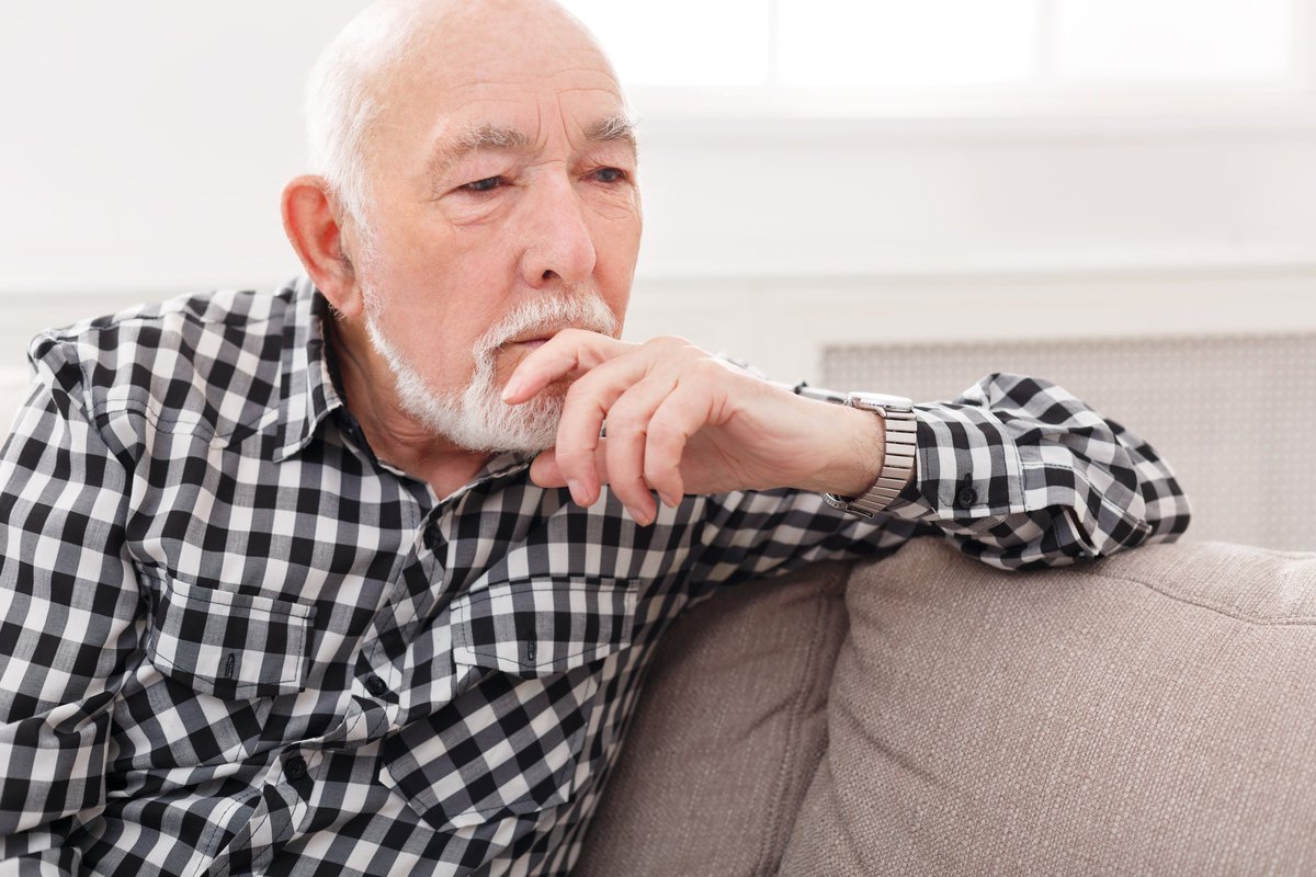 Pensive elderly man on sofa.