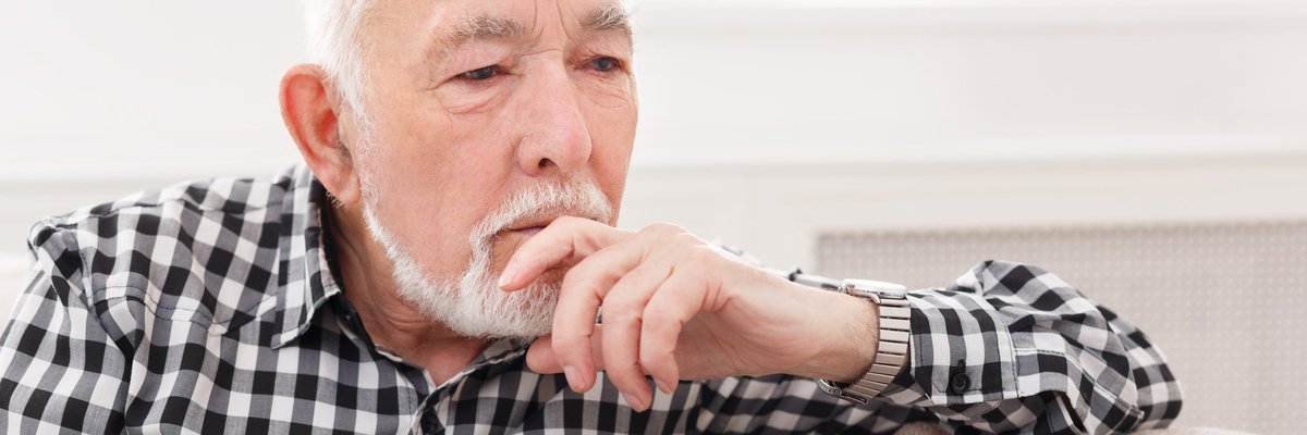 Pensive elderly man on sofa.
