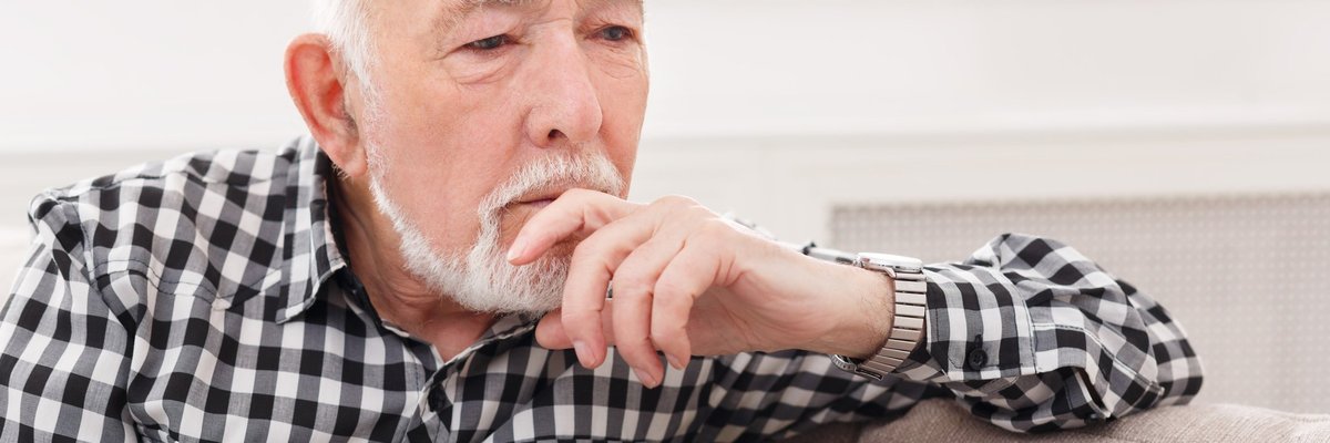 Pensive elderly man on sofa.
