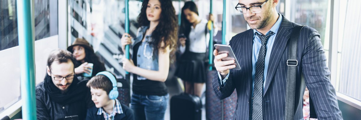 People on a bus, with several using their cell phones.