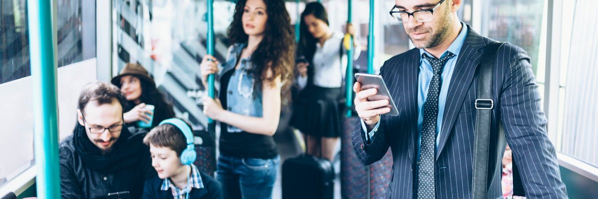People on a bus, with several using their cell phones.