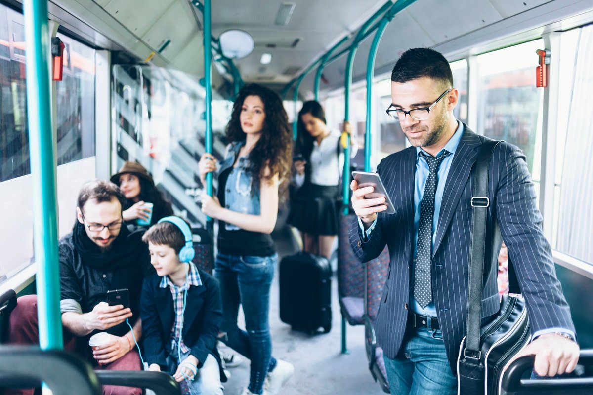 People on a bus, with several using their cell phones.