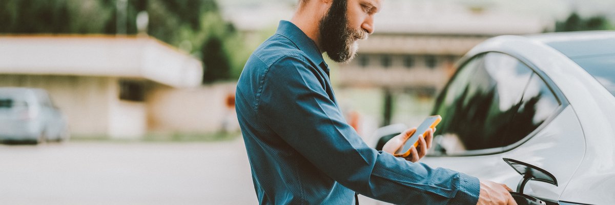 Person connecting their EV to power source while looking at cellphone