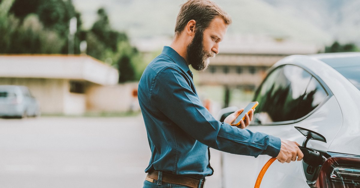 Person connecting their EV to power source while looking at cellphone