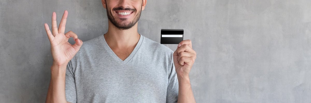 A smiling person holding a credit card.