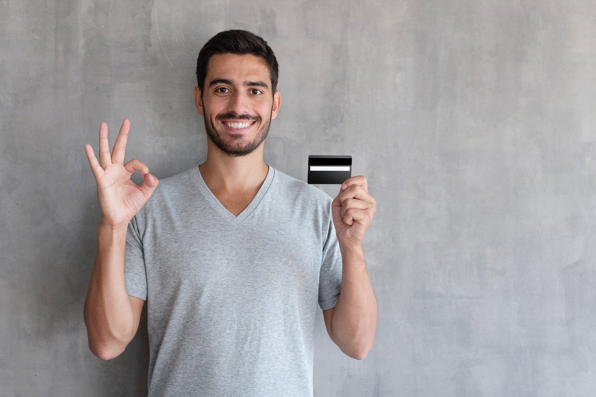 A smiling person holding a credit card.