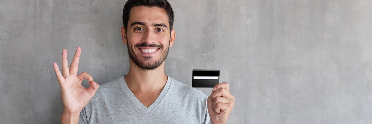 A smiling person holding a credit card.