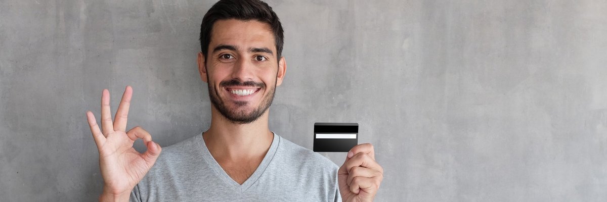 A smiling person holding a credit card.