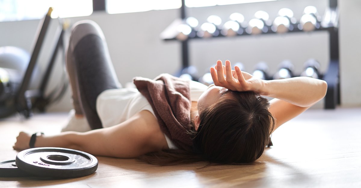 Person resting on floor in room filled with weights and workout equipment.