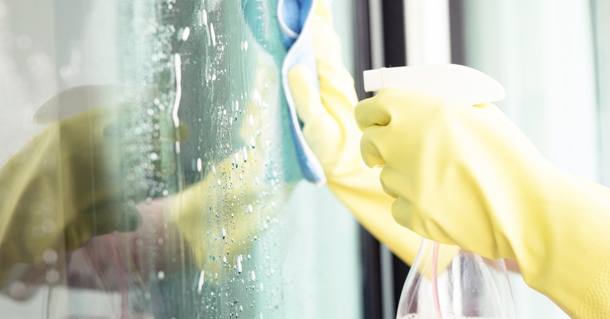 Person with rubber gloves on cleaning a window.