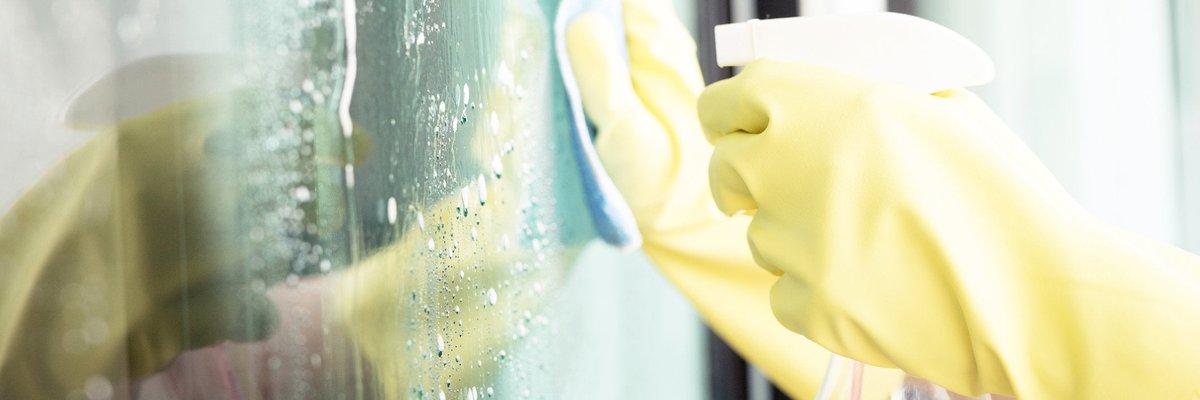 Person with rubber gloves on cleaning a window.
