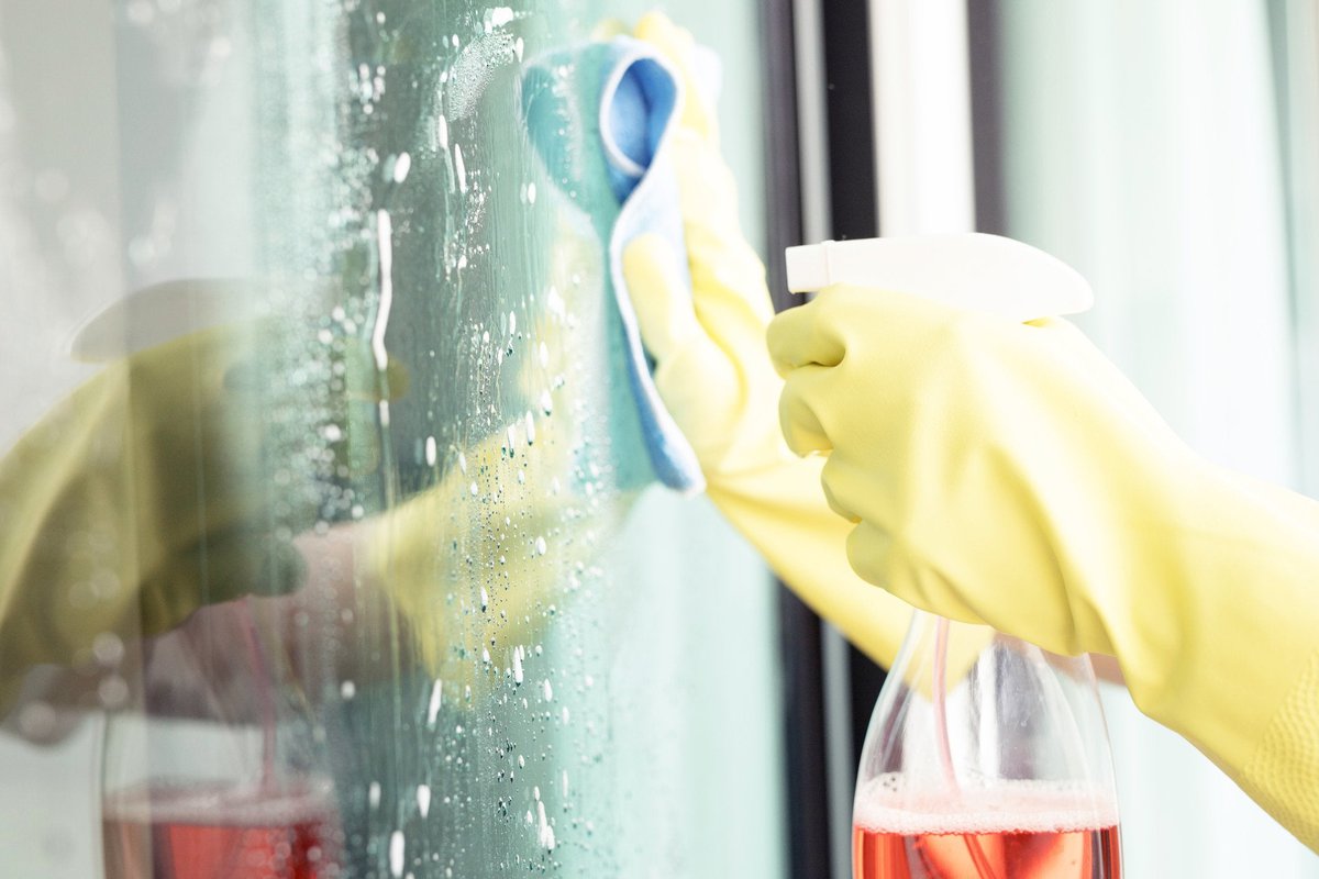 Person with rubber gloves on cleaning a window.