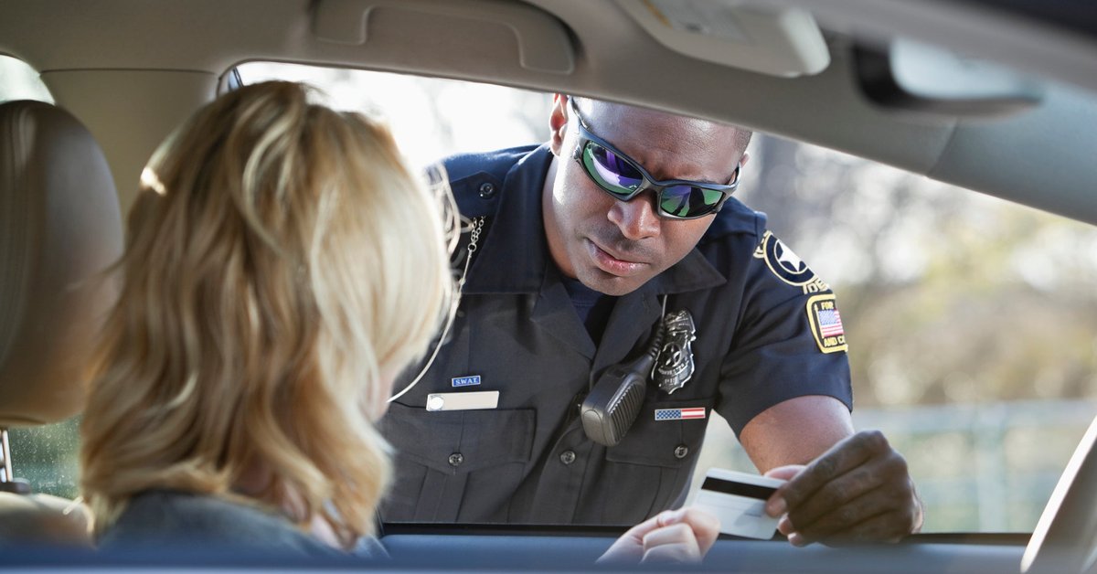 Police officer taking drivers license from woman he has pulled over.