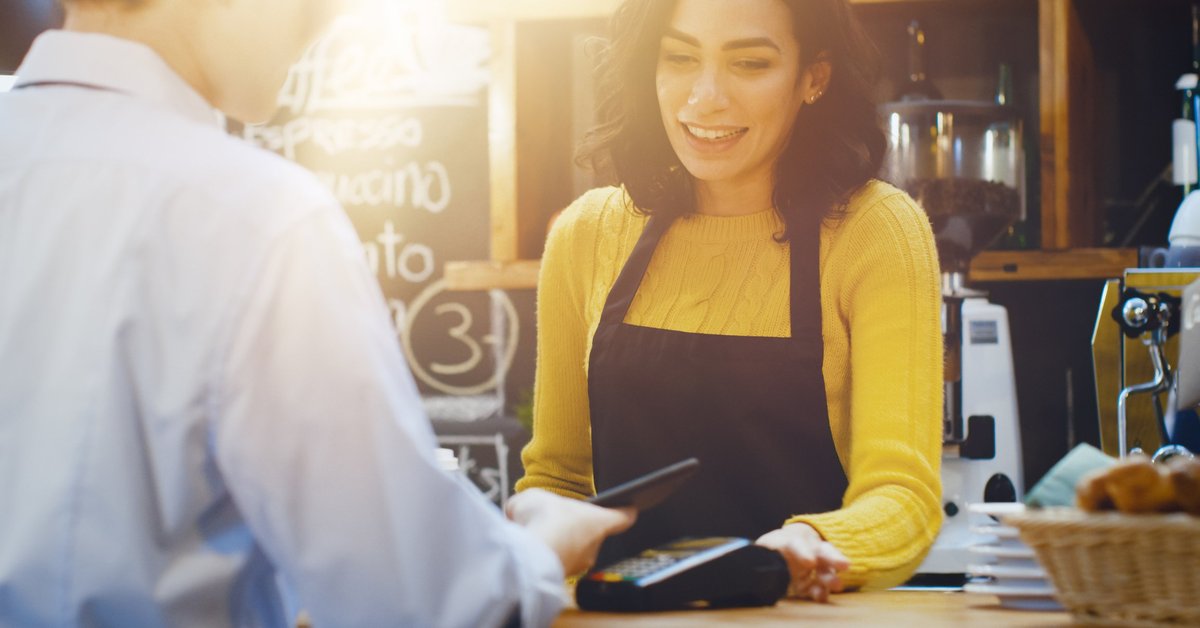 Cashier watching as customer pays with a credit card.