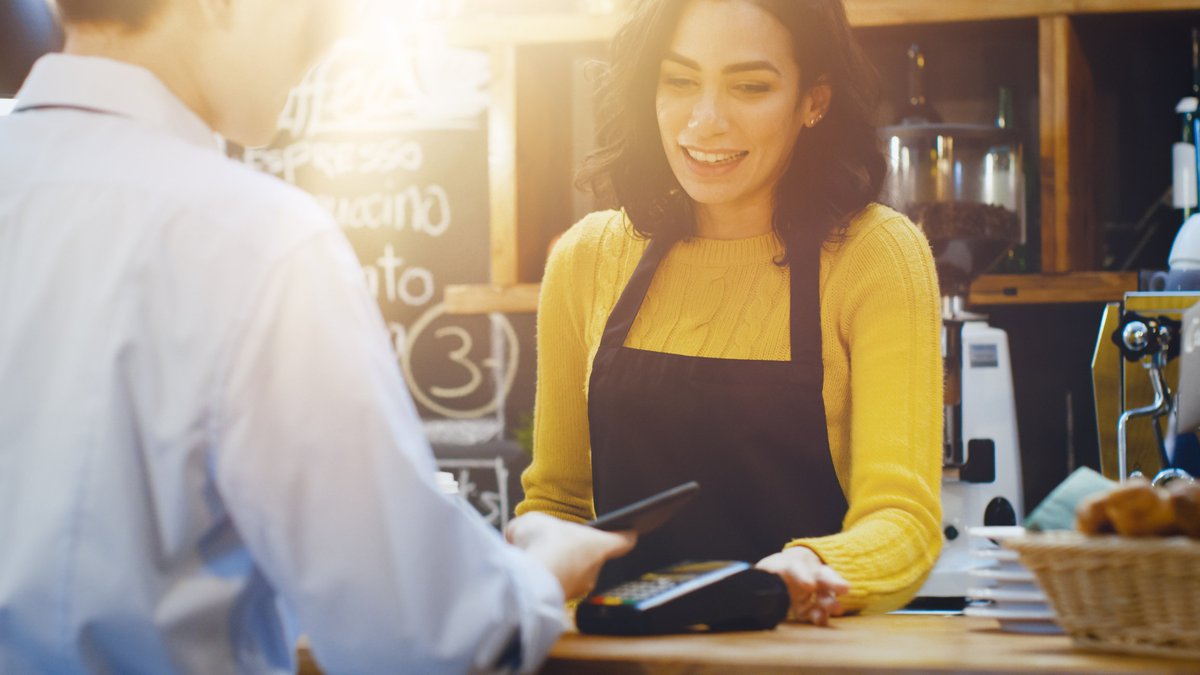 Cashier watching as customer pays with a credit card.