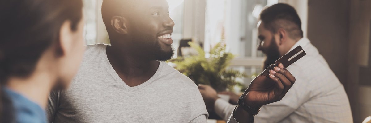Smiling man paying with his credit card at a restaurant.