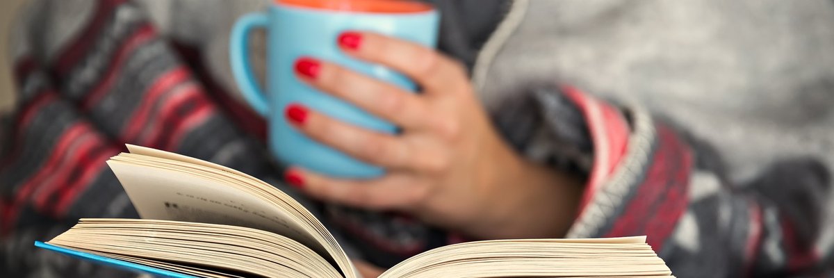 Woman holding a mug, reading a book