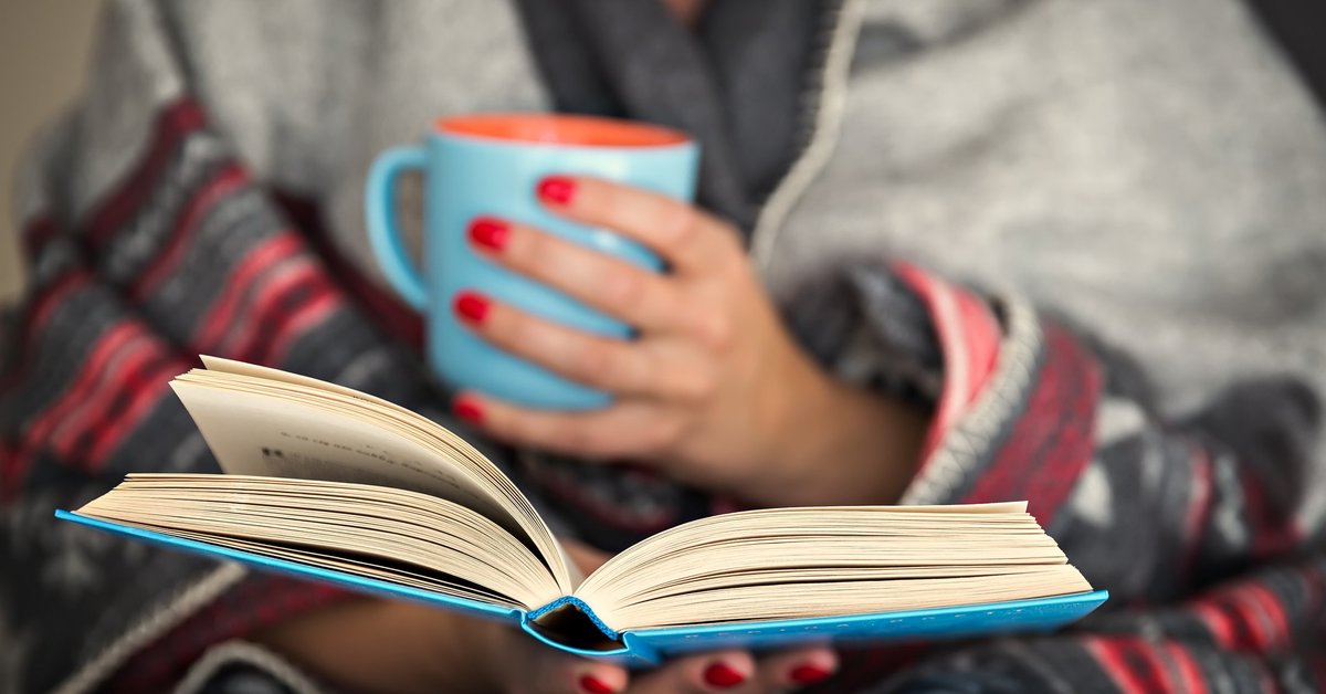 Woman holding a mug, reading a book
