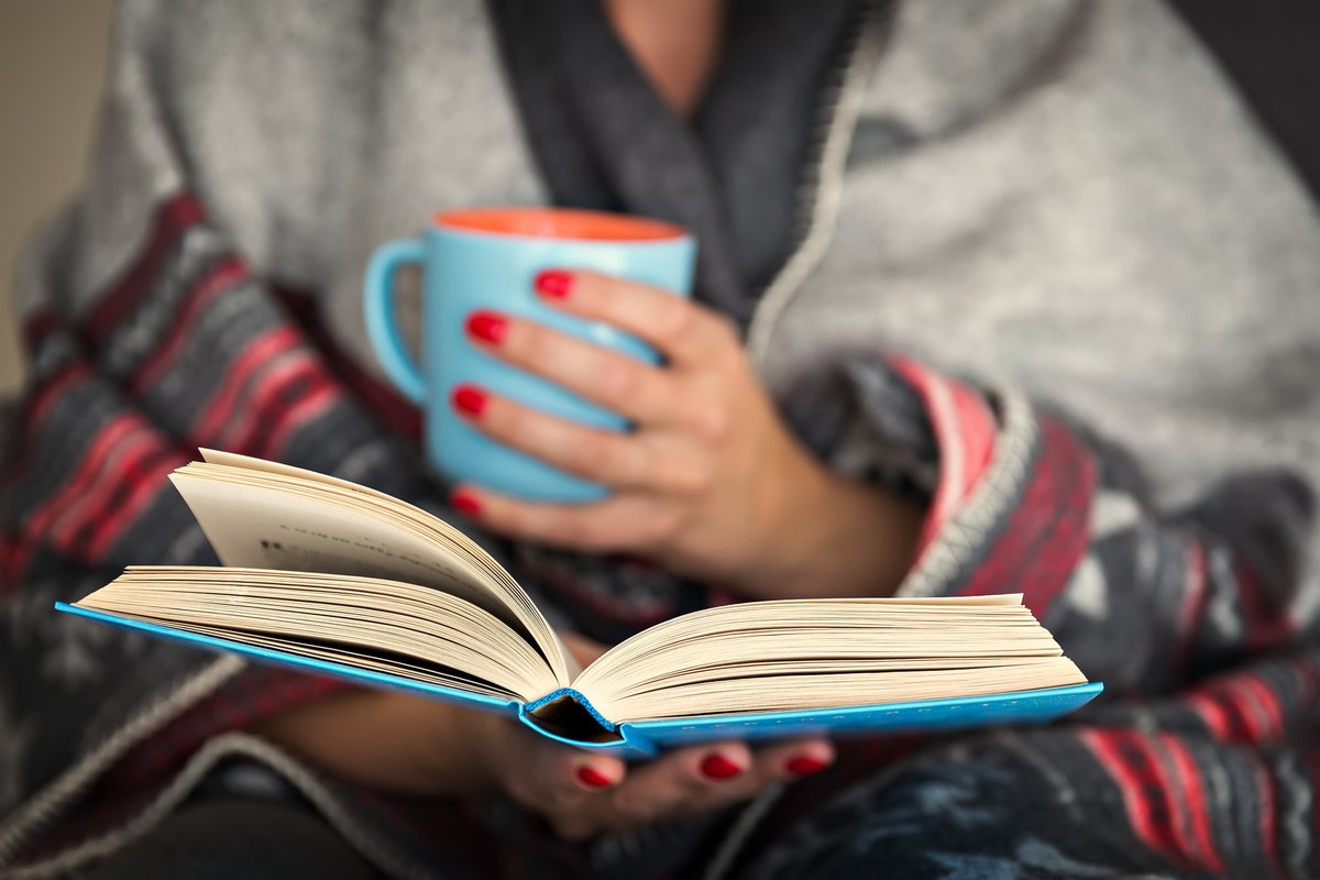 Woman holding a mug, reading a book