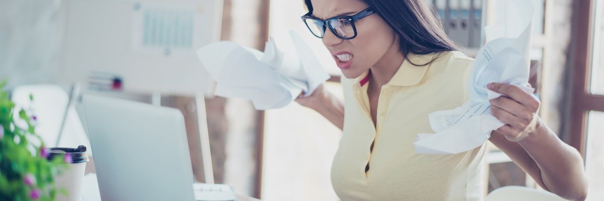 Angry Woman Crumpling Papers And Snarling At Laptop