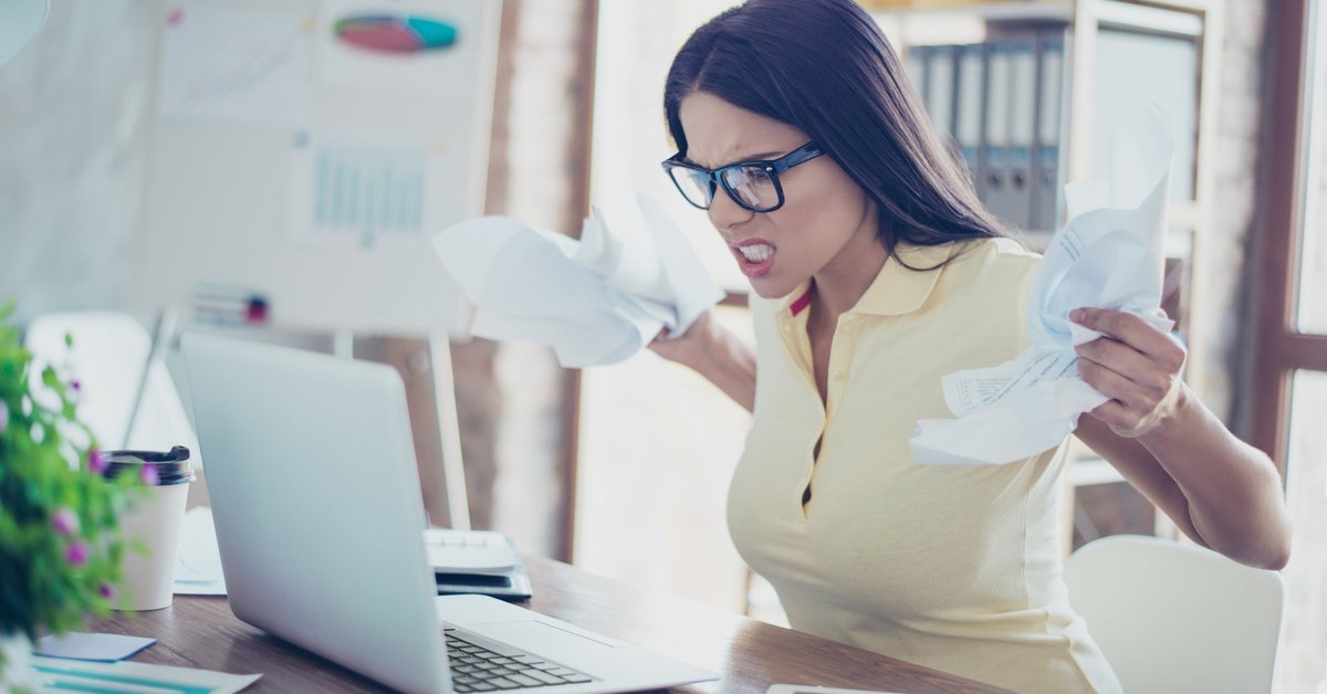 Angry Woman Crumpling Papers And Snarling At Laptop