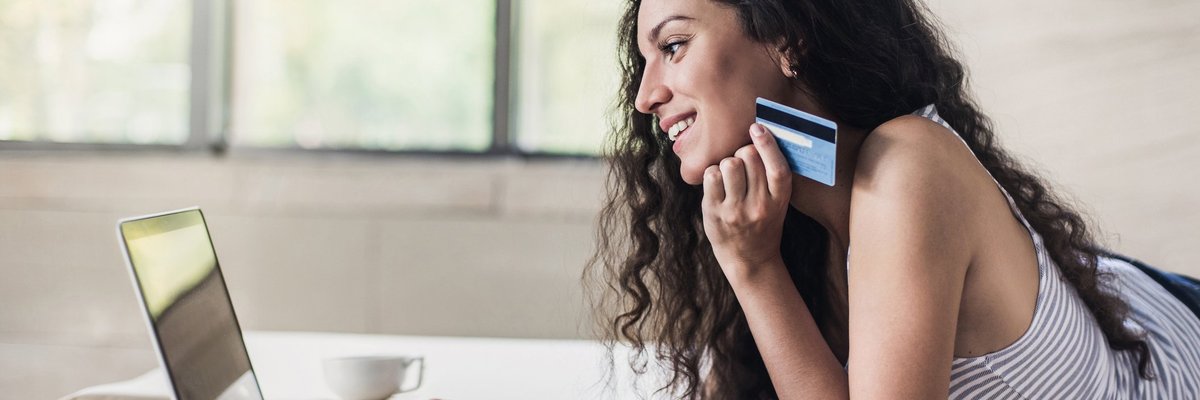 Woman holding credit card and shopping on a laptop.