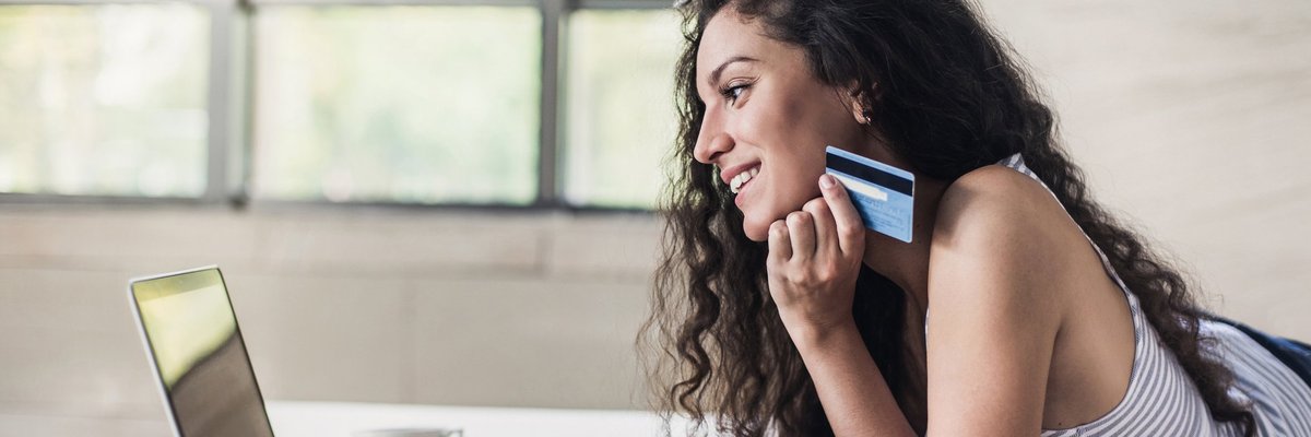 Woman holding credit card and shopping on a laptop.
