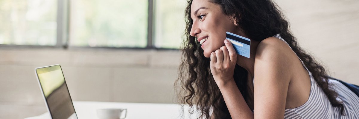 Woman holding credit card while using a laptop.