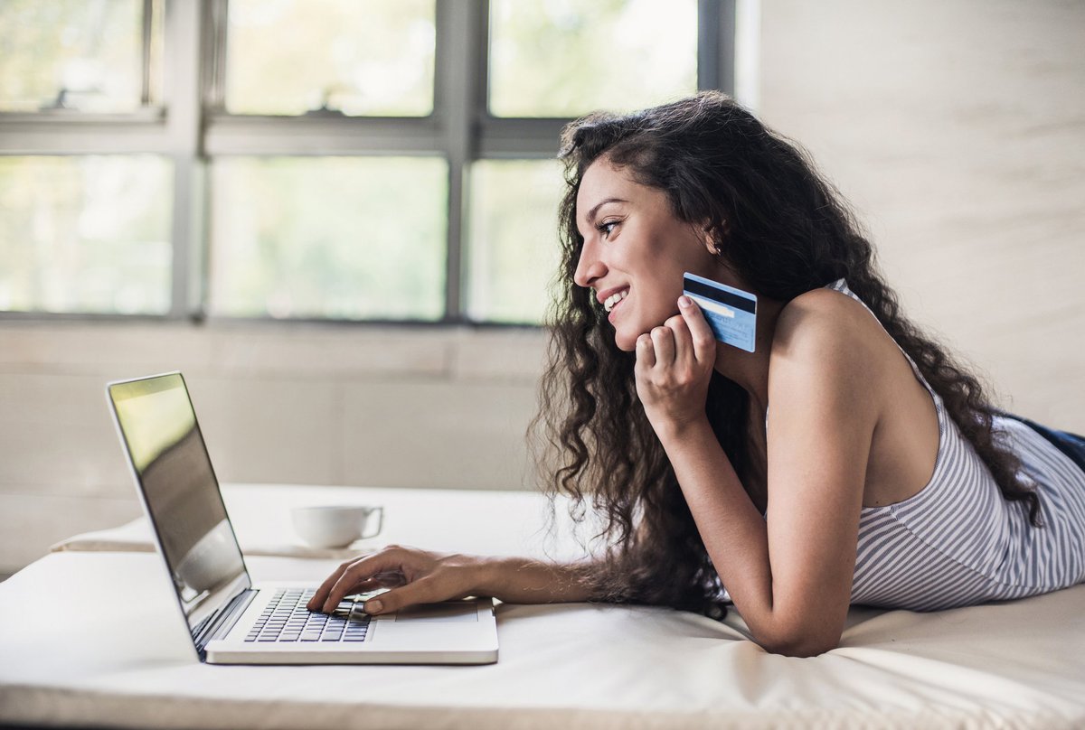 Woman holding credit card and shopping on a laptop.
