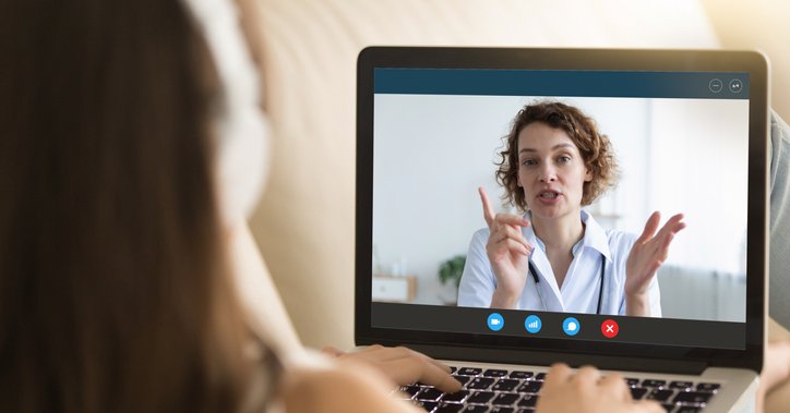 A woman talks to a doctor via her computer