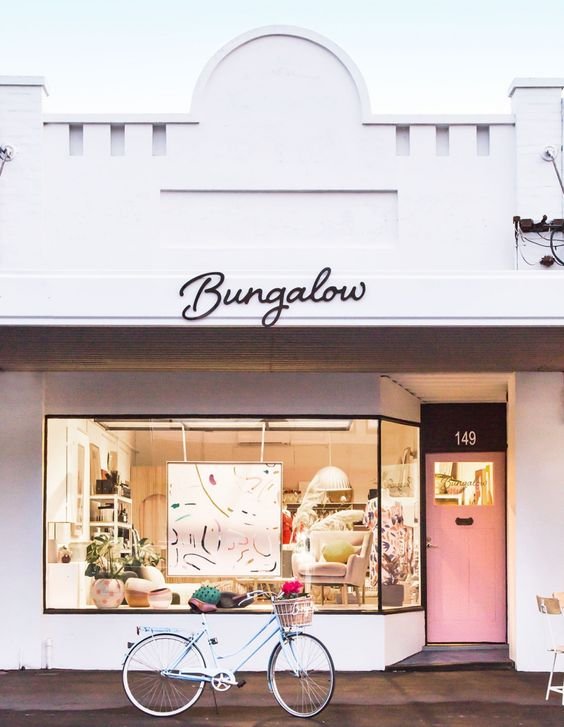 Image of a white retail store with a pink door and a sign that says Bungalow.