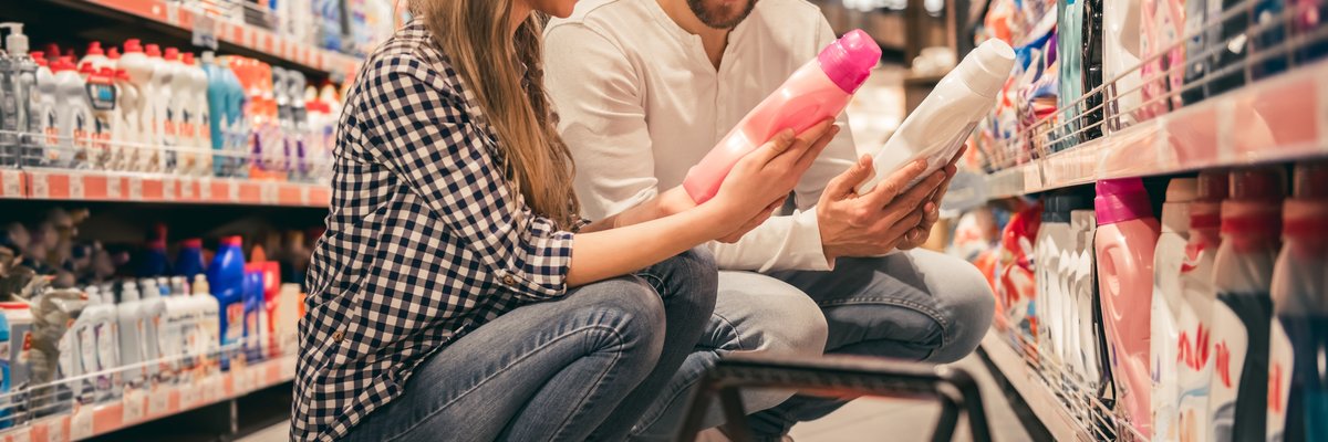 Couple comparing cleaning products in a store aisle.