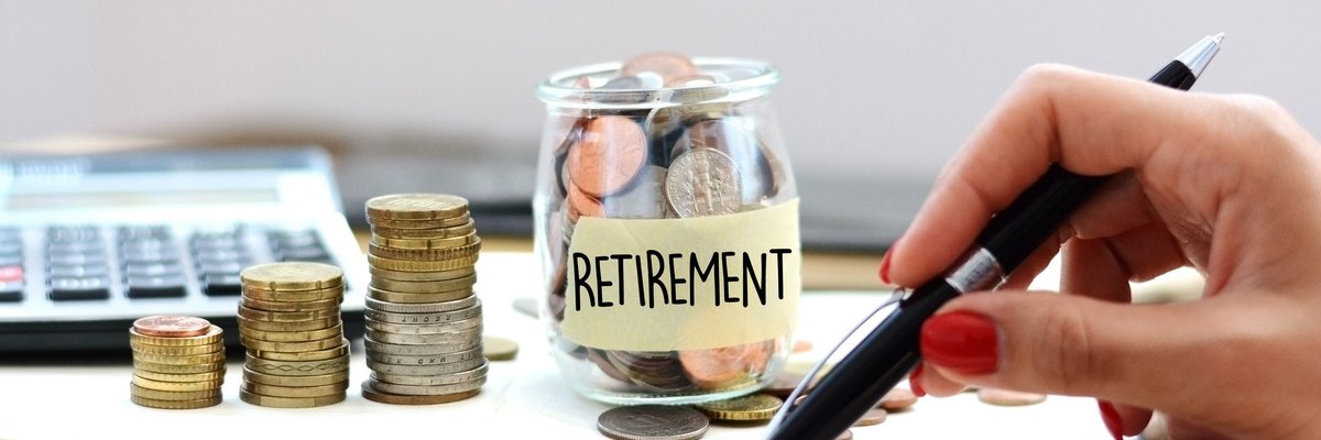A glass jar full of coins labeled Retirement and with coins stacked next to it as well.