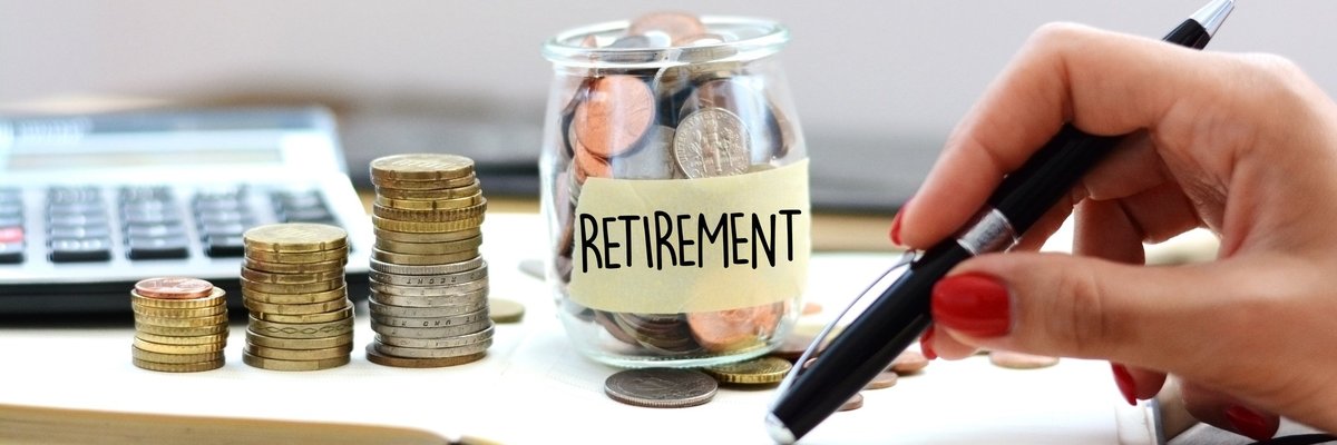 A glass jar full of coins labeled Retirement and with coins stacked next to it as well.