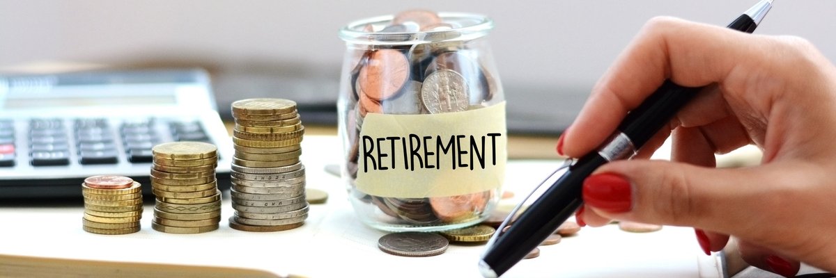 A glass jar full of coins labeled Retirement and with coins stacked next to it as well.