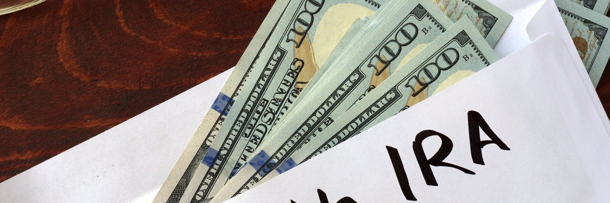 An envelope with Roth IRA written on it and $100 bills falling out.