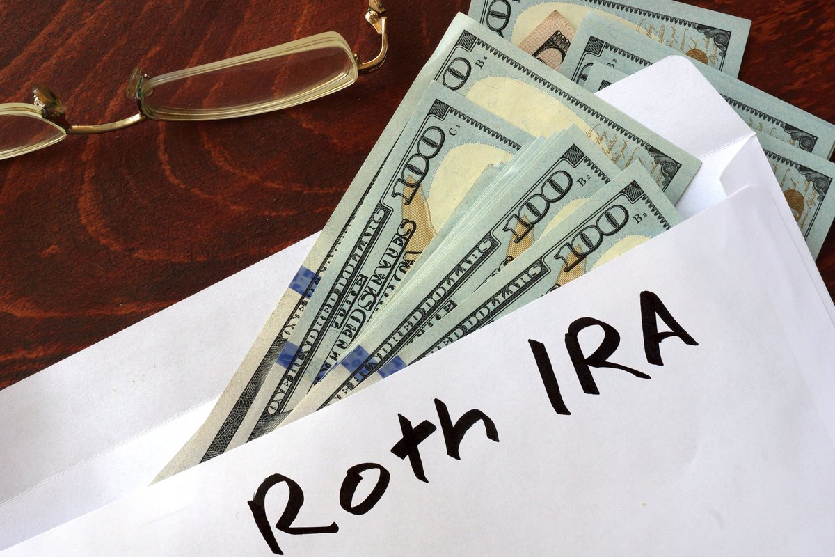 An envelope with Roth IRA written on it and $100 bills falling out.
