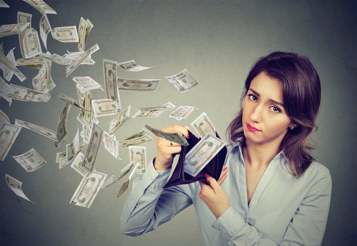 Sad woman with money flying out of wallet