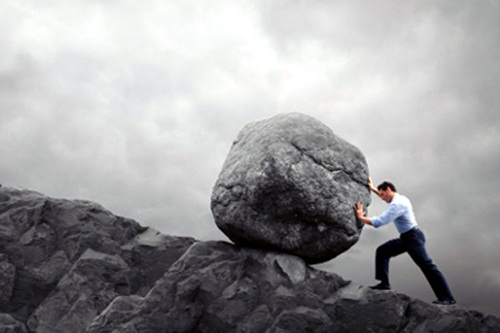 Businessman pushing a boulder.