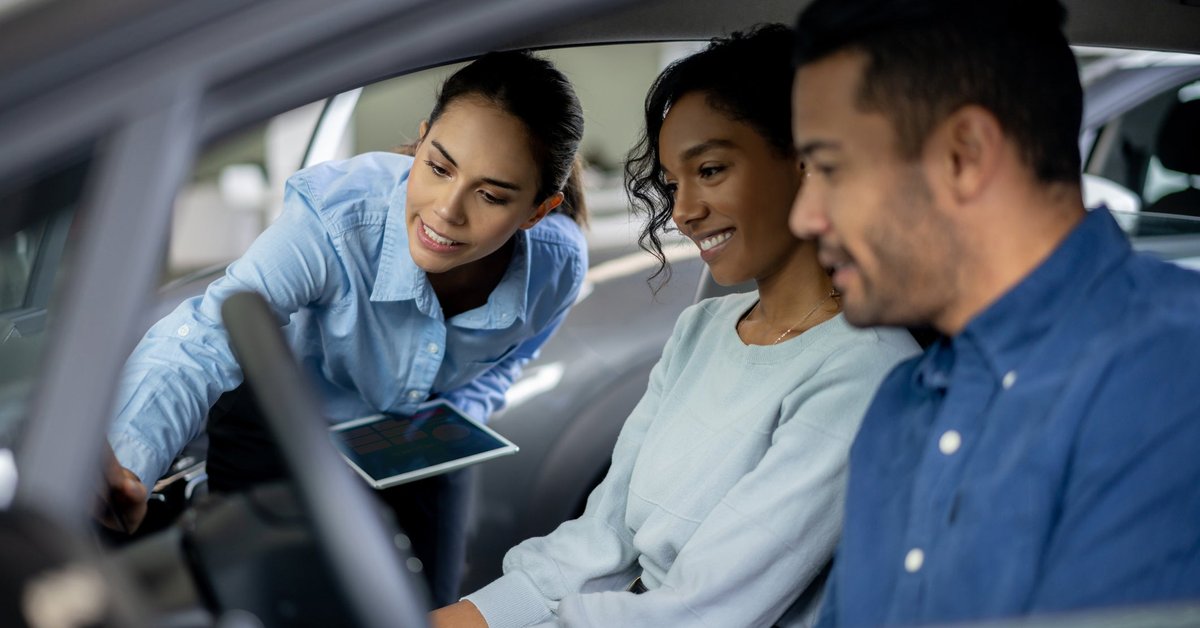 Salesperson showing couple features inside a car.